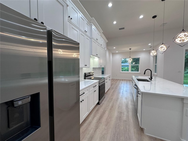 kitchen featuring white cabinets, an island with sink, stainless steel appliances, and sink