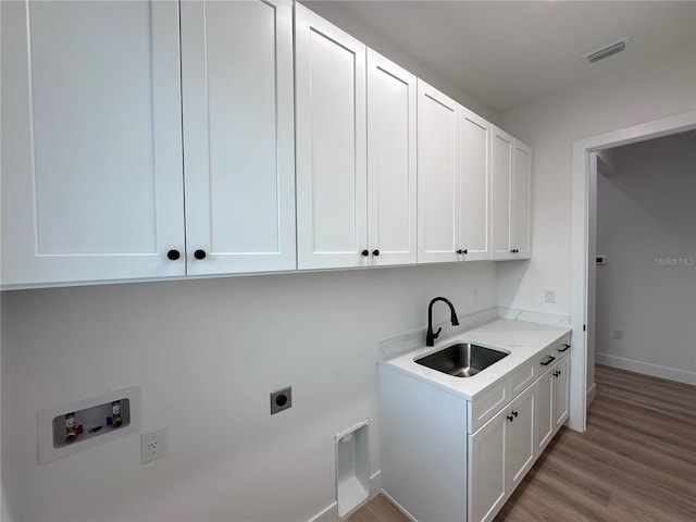 laundry room featuring sink, hookup for an electric dryer, cabinets, hookup for a washing machine, and light hardwood / wood-style floors