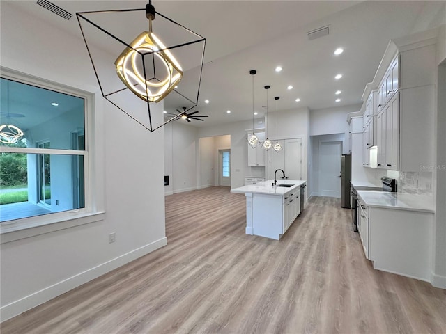 kitchen with ceiling fan, pendant lighting, white cabinets, sink, and light hardwood / wood-style flooring