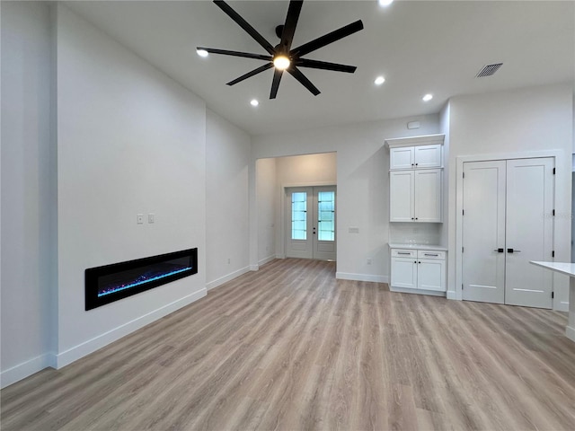 unfurnished living room featuring light hardwood / wood-style flooring, ceiling fan, and french doors