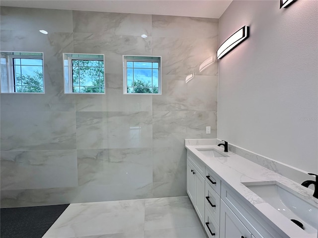 bathroom with a tile shower, vanity, and plenty of natural light