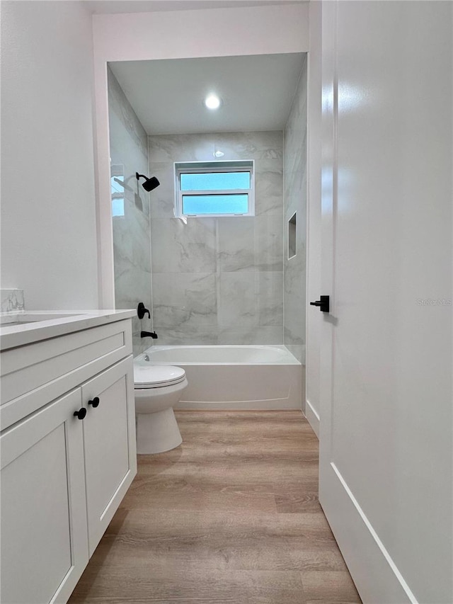 full bathroom with vanity, hardwood / wood-style flooring, tiled shower / bath combo, and toilet