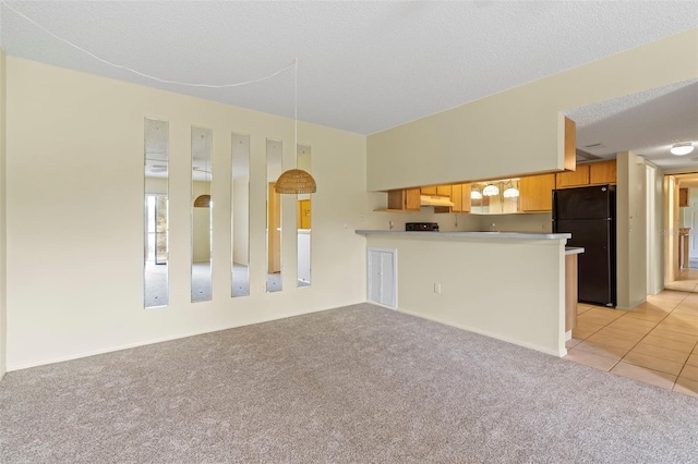 kitchen featuring hanging light fixtures, light colored carpet, black refrigerator, kitchen peninsula, and a textured ceiling