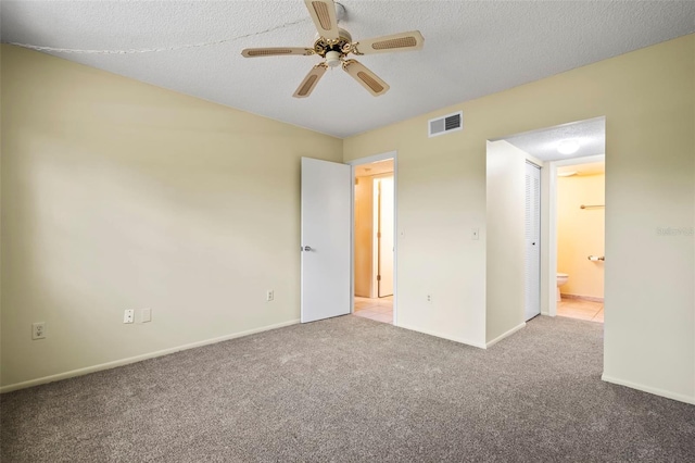 interior space with ensuite bath, a textured ceiling, ceiling fan, and light colored carpet