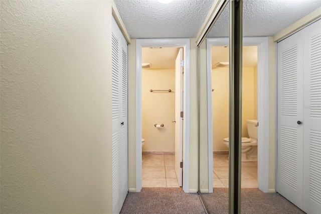 hall featuring light carpet and a textured ceiling