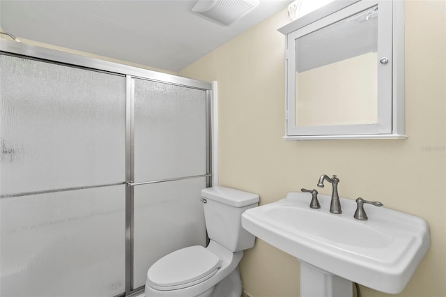 bathroom with toilet, a shower with door, and sink