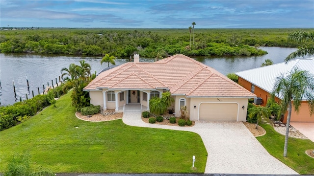 view of front of house with a front yard, a garage, and a water view