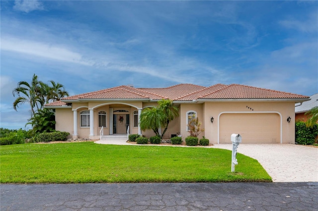 mediterranean / spanish-style house with a garage and a front lawn