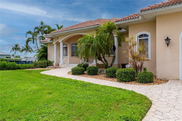 doorway to property with a yard, a tiled roof, and stucco siding