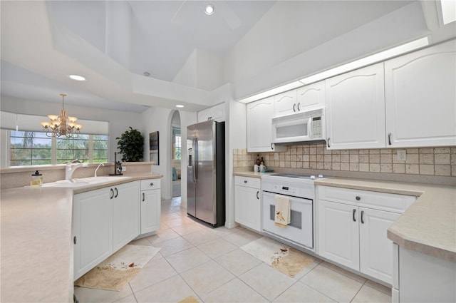 kitchen with pendant lighting, white appliances, white cabinetry, and an inviting chandelier