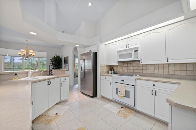 kitchen with white appliances, light countertops, hanging light fixtures, and white cabinetry