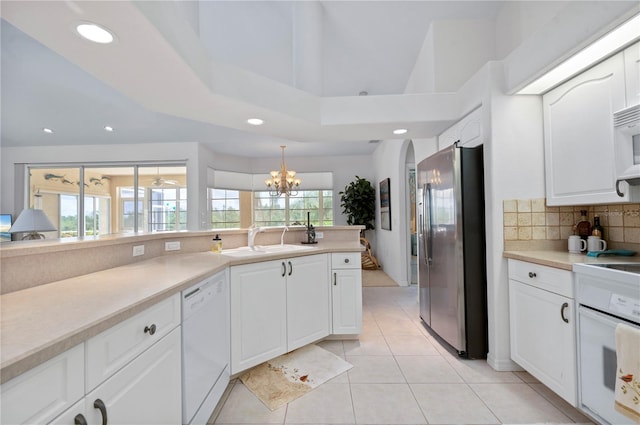 kitchen with white appliances, a sink, white cabinetry, light countertops, and pendant lighting