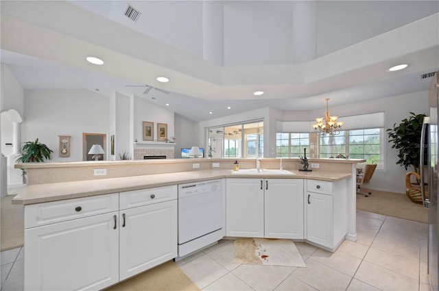 kitchen featuring dishwasher, decorative light fixtures, a tiled fireplace, and white cabinetry