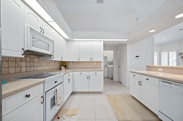 kitchen with light tile patterned floors, light countertops, white appliances, and white cabinets