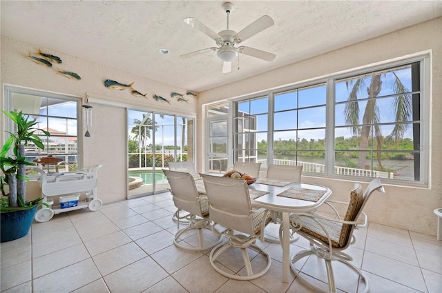 sunroom with a water view and ceiling fan