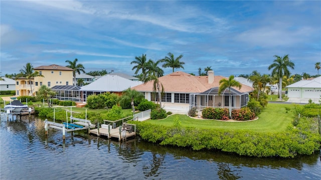 back of house featuring a lawn, a water view, and a lanai