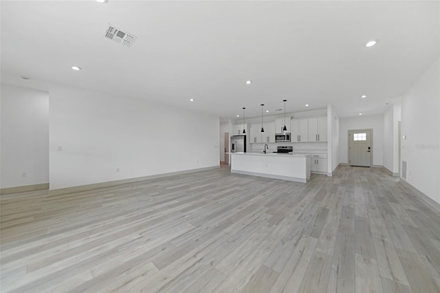 unfurnished living room featuring sink and light hardwood / wood-style flooring