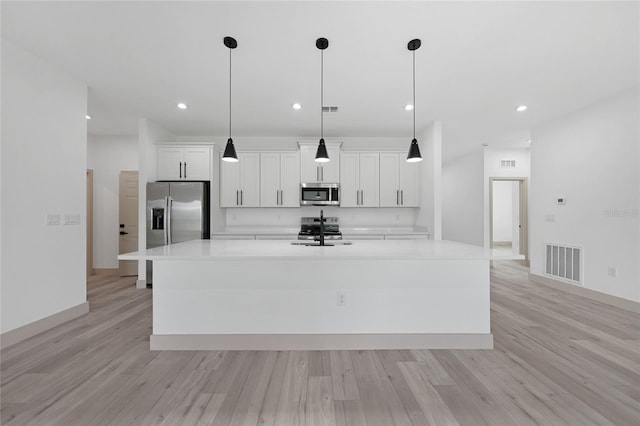 kitchen featuring an island with sink, light hardwood / wood-style floors, and appliances with stainless steel finishes