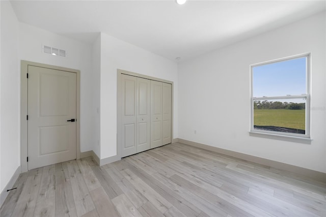 unfurnished bedroom with light hardwood / wood-style floors and a closet