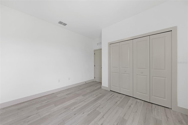 unfurnished bedroom featuring light wood-type flooring and a closet