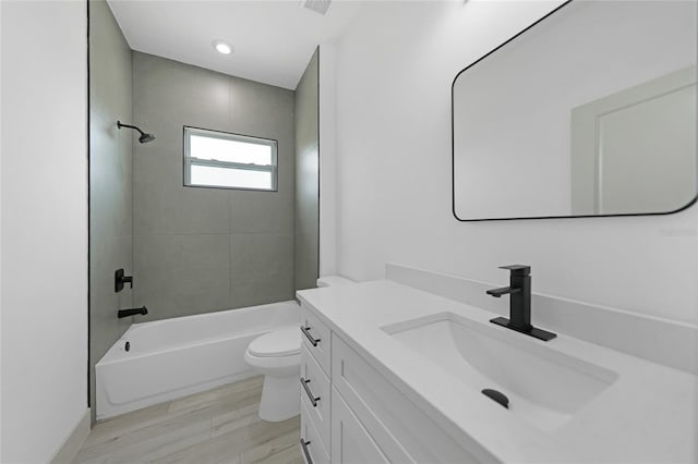 full bathroom featuring hardwood / wood-style floors, vanity, toilet, and tiled shower / bath