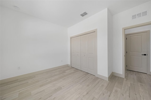 unfurnished bedroom with light wood-type flooring and a closet