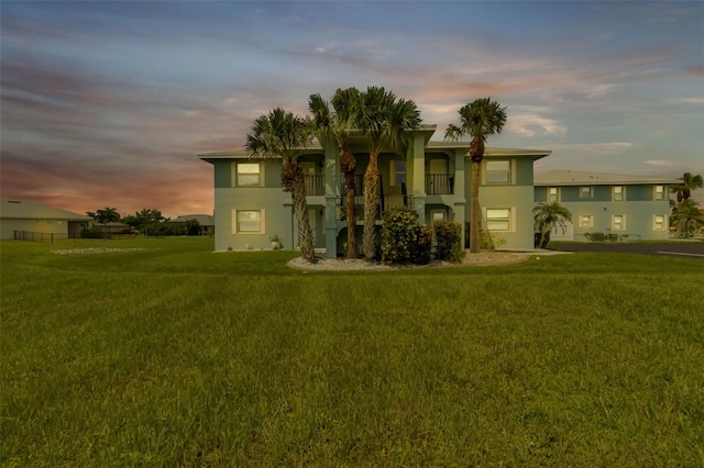 view of front of home with a balcony and a lawn