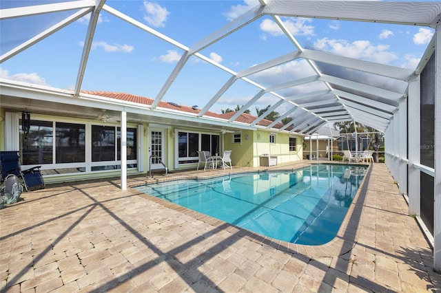 pool with ceiling fan, glass enclosure, and a patio area