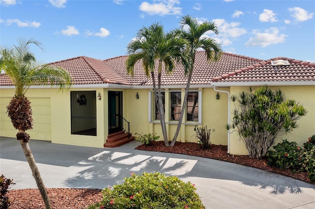 view of front of property with an attached garage, a tiled roof, concrete driveway, and stucco siding