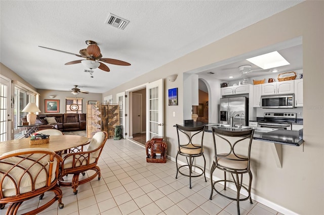 kitchen with appliances with stainless steel finishes, dark countertops, a kitchen bar, and visible vents