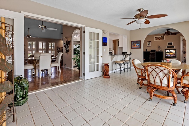 dining space featuring arched walkways, ceiling fan, and light tile patterned floors