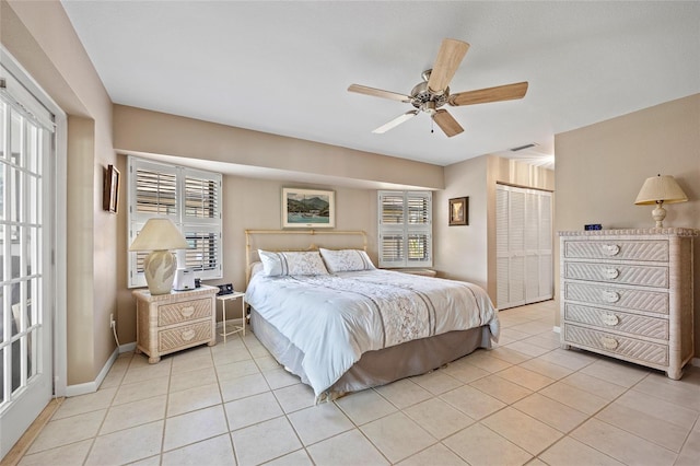 bedroom featuring light tile patterned floors, a closet, a ceiling fan, and baseboards