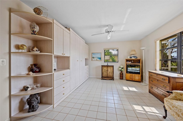 interior space featuring light tile patterned floors, baseboards, and a ceiling fan