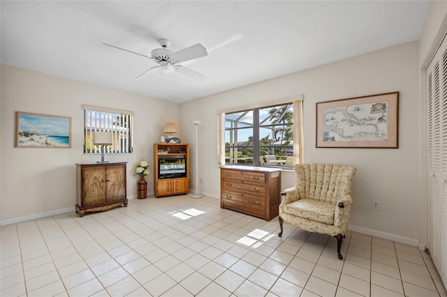 living area featuring ceiling fan, baseboards, and light tile patterned flooring