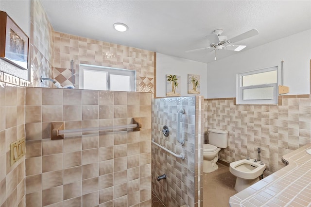 full bath with tile walls, toilet, a bidet, a textured ceiling, and a walk in shower