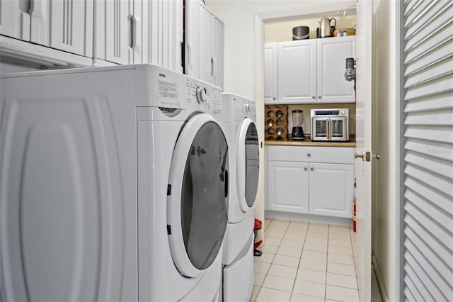 clothes washing area featuring light tile patterned floors and washer and clothes dryer