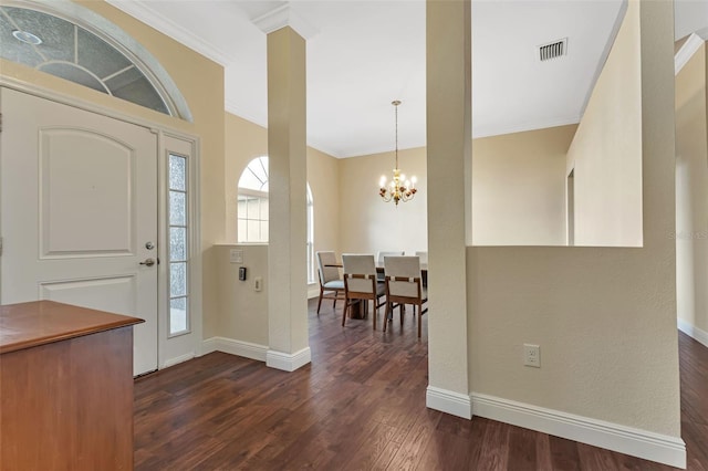 foyer with dark wood-type flooring, crown molding, and a notable chandelier