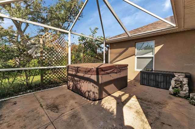 view of patio / terrace featuring a hot tub and a lanai