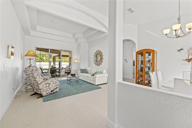 living room featuring a chandelier, a tray ceiling, and a towering ceiling