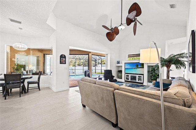 tiled living room featuring high vaulted ceiling, a textured ceiling, and ceiling fan