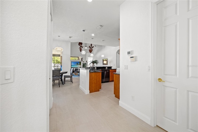 interior space featuring pendant lighting, kitchen peninsula, dishwashing machine, a kitchen island, and a chandelier