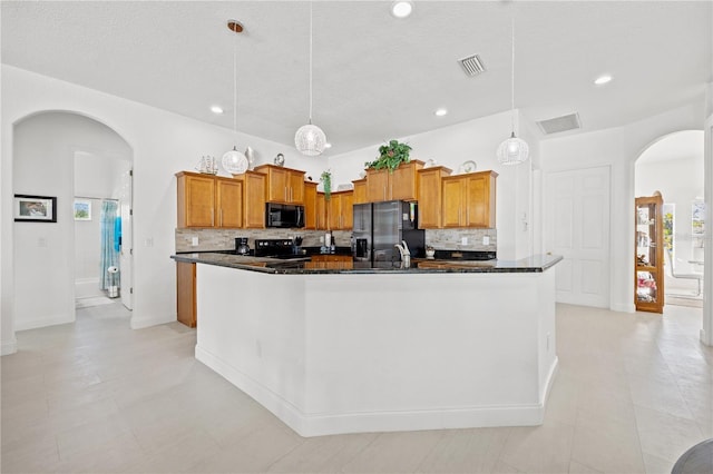 kitchen featuring light tile patterned floors, range, stainless steel fridge with ice dispenser, and a center island with sink