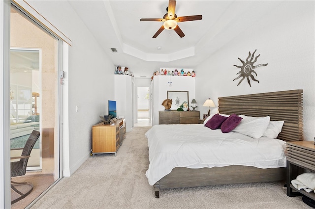 carpeted bedroom with ceiling fan and a tray ceiling