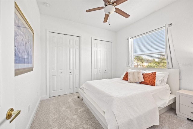 carpeted bedroom featuring multiple closets and ceiling fan