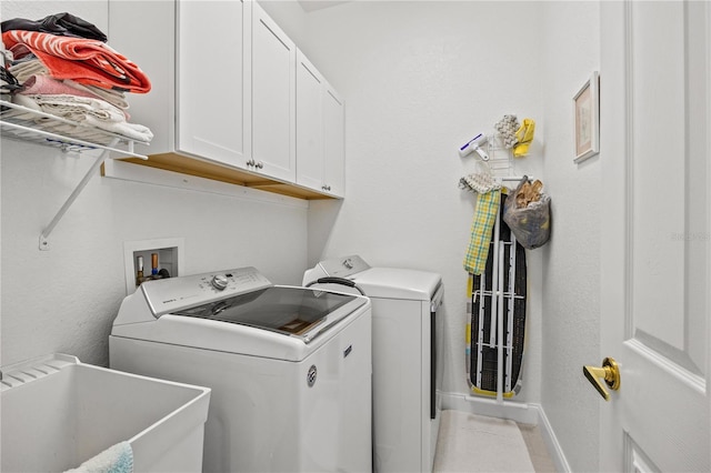 laundry area with tile patterned flooring, washing machine and dryer, sink, and cabinets