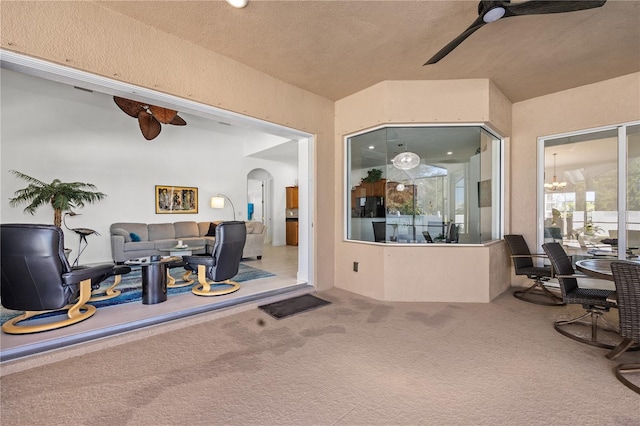 interior space with a textured ceiling, ceiling fan, and carpet flooring