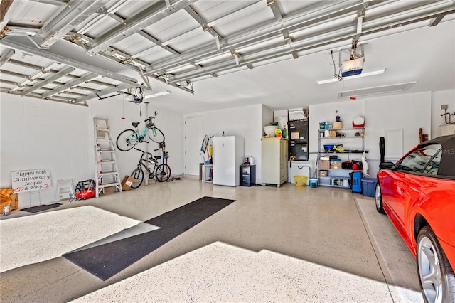 garage featuring white refrigerator and a garage door opener