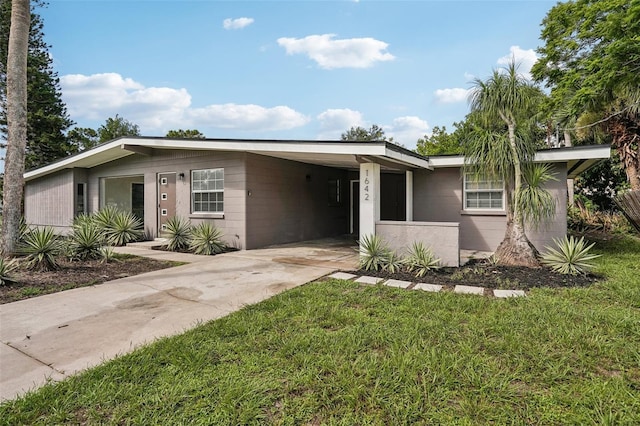 1642 Banyan Dr, Venice, FL 34293 - view of front facade with concrete driveway, a carport, a front yard, and concrete block siding