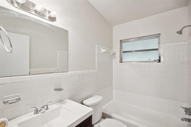 full bathroom with vanity, tile walls, toilet, and tiled shower / bath combo