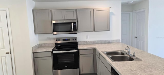 kitchen with light countertops, stainless steel appliances, gray cabinets, and a sink